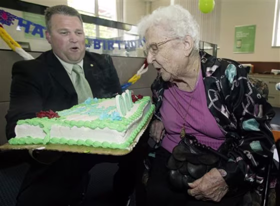 June Gregg, right, of Bainbridge, Ohio, blows out the candles on her birthday cake held by Doug Shoemaker, community president and branch general manager of the Chillicothe branch of Huntington National Bank, to celebrate Gregg's 100th birthday.
